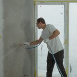 Commercial painter with sprayer painting a wall