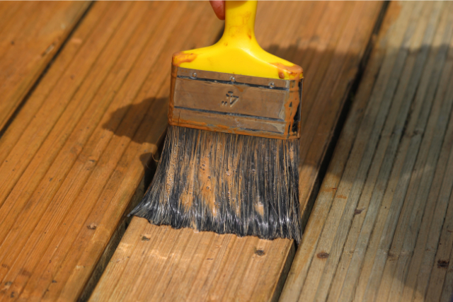 Worker performing deck painting with brush