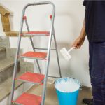 Wall painting worker with paint bucket and ladder